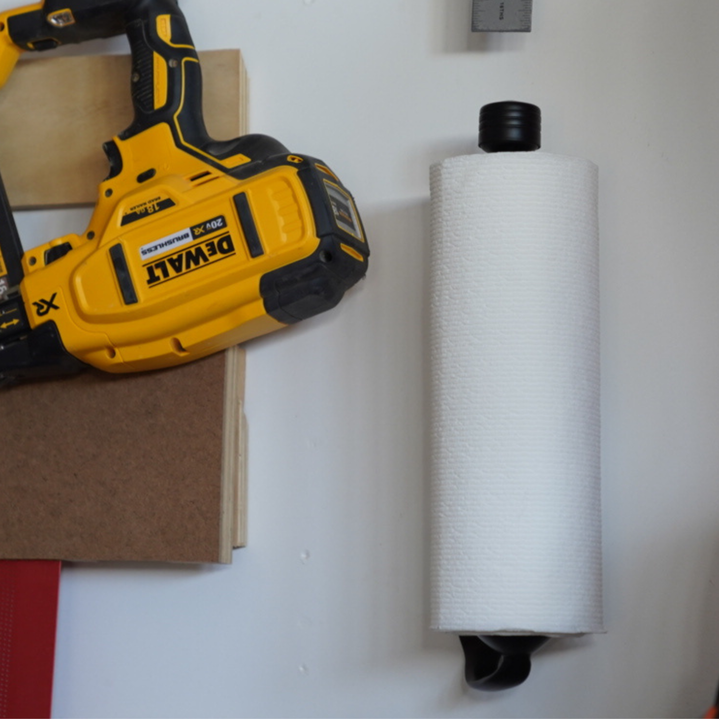 DeWalt power tool and black mounted paper towel on a white surface