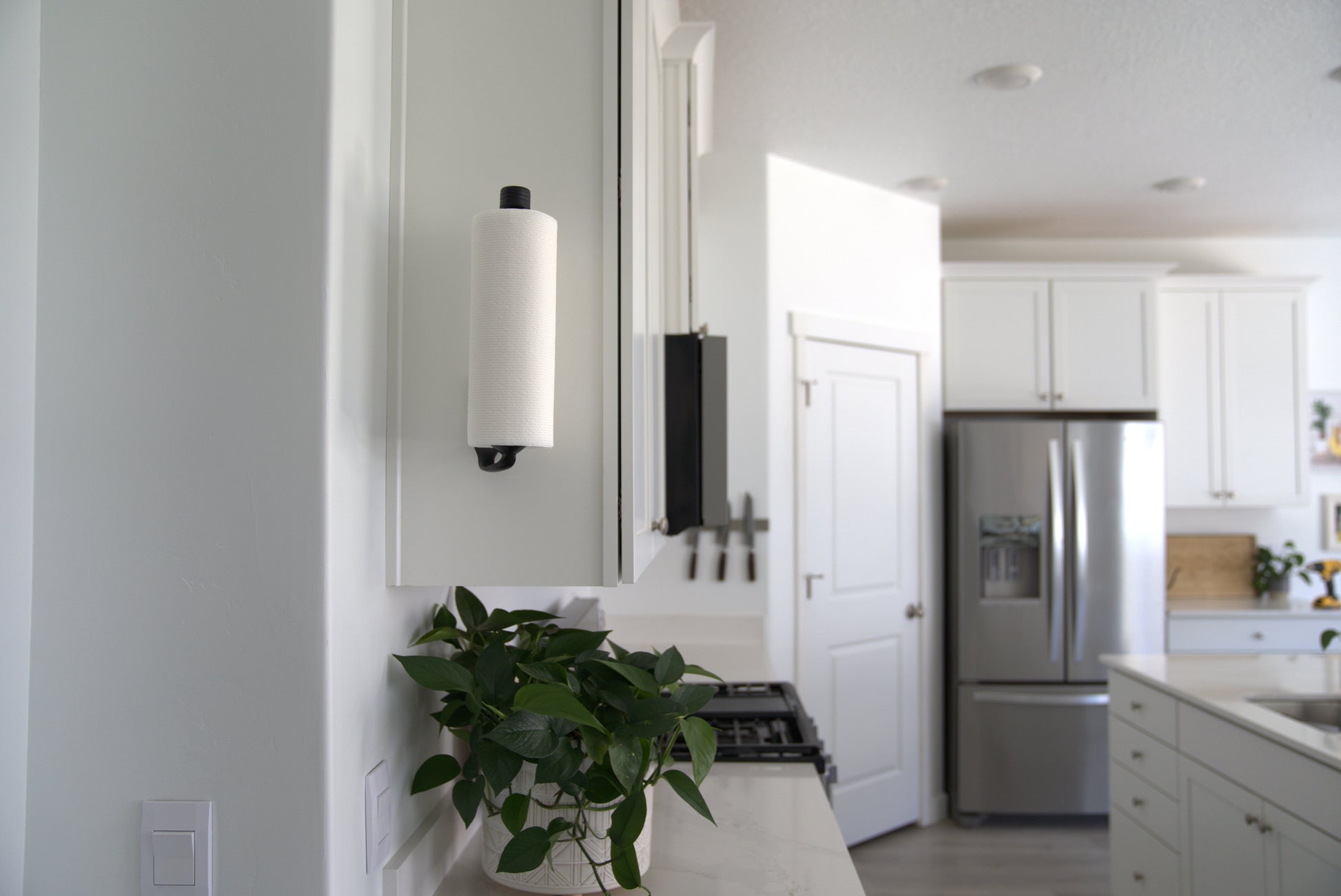 Modern kitchen with stainless steel refrigerator, white cabinets, and a plant on the counter.