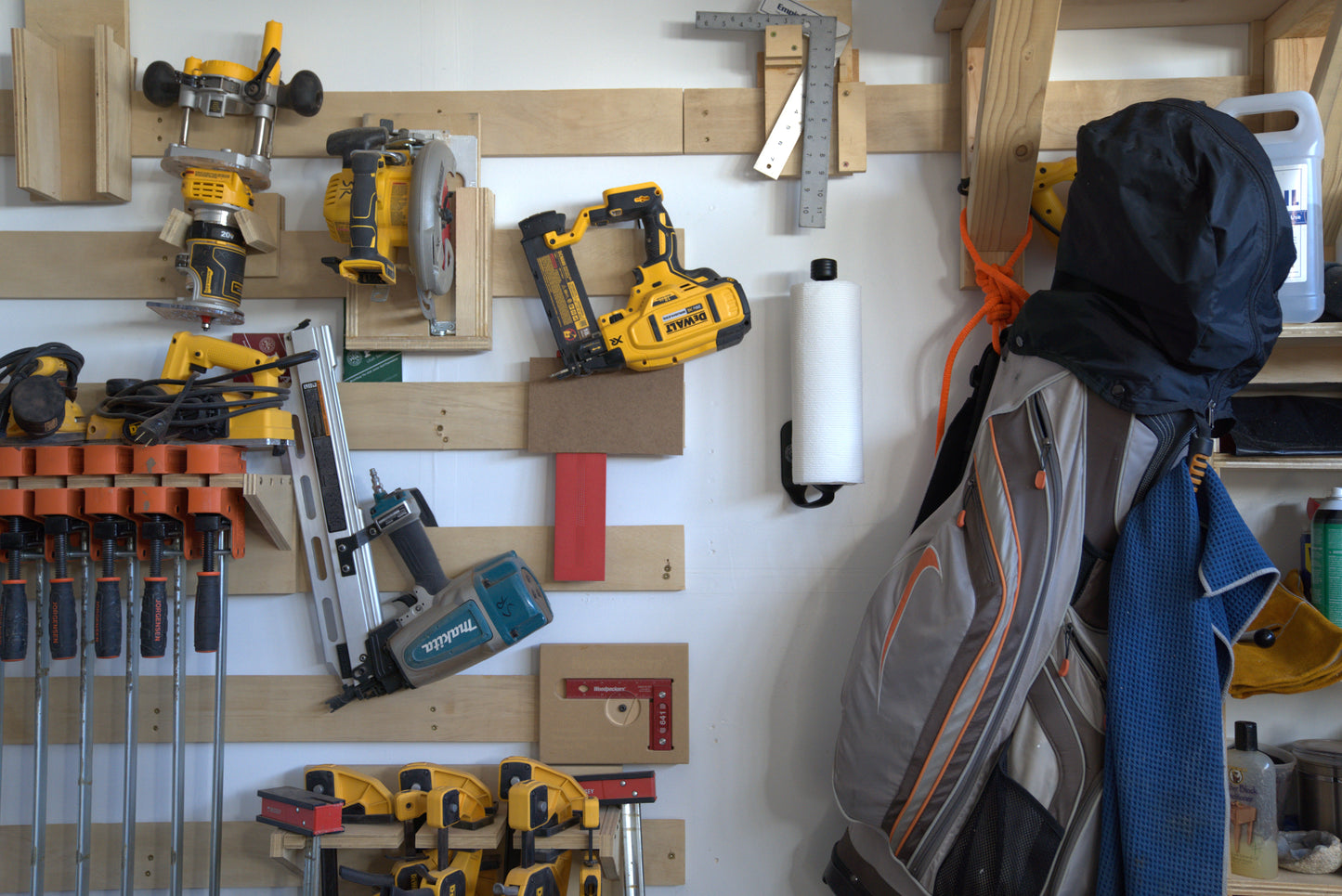 Wall-mounted tool organization system with various power tools and a backpack.
