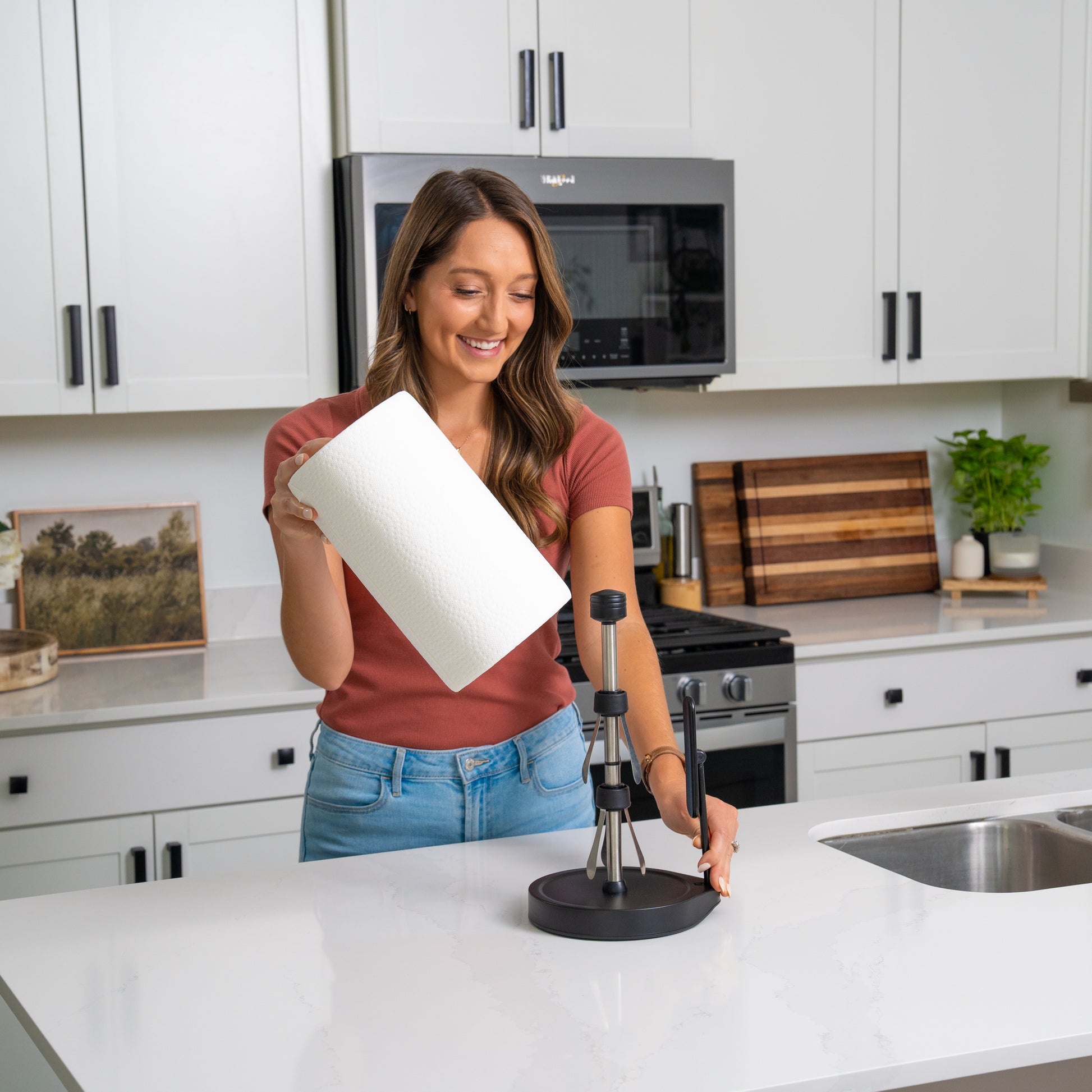 Woman in kitchen putting in new roll of paper on the black tension arm paper towel holder