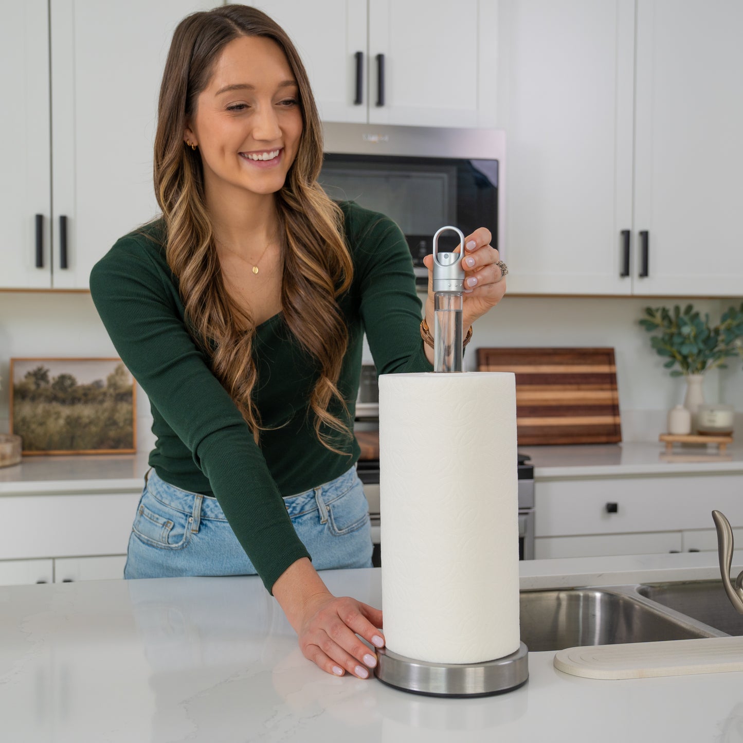 Woman in a kitchen holding a smart paper towel holder with built in sprayer